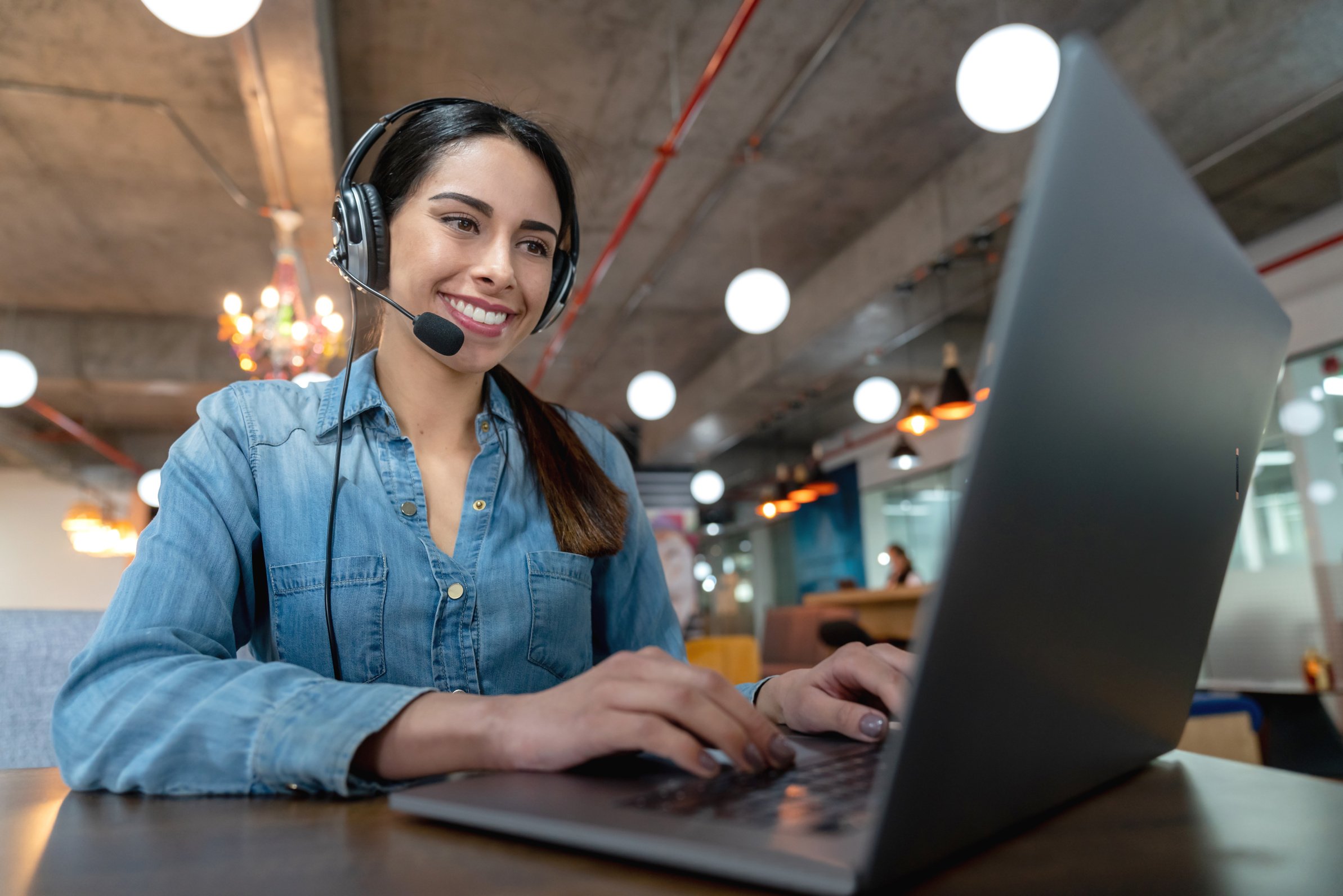 Beautiful woman on a virtual meeting using her laptop and headset smiling