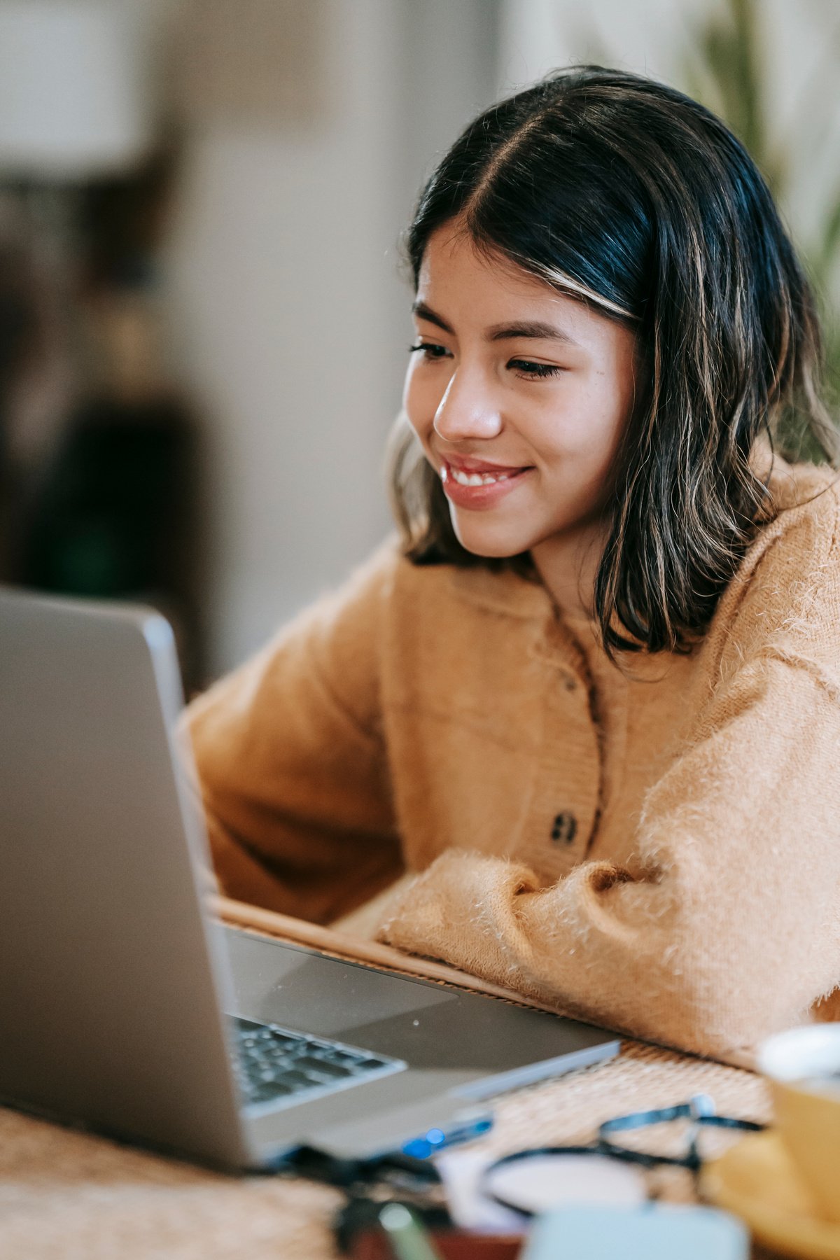 Smiling ethnic distance employee working on laptop in house